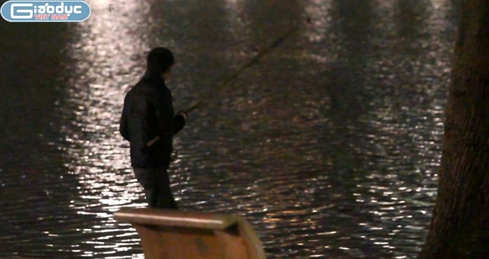 Một "câu tặc" ven Hồ Gươm chăm chú quan sát phao câu được thả dưới Hồ Gươm giữa đêm mưa rét